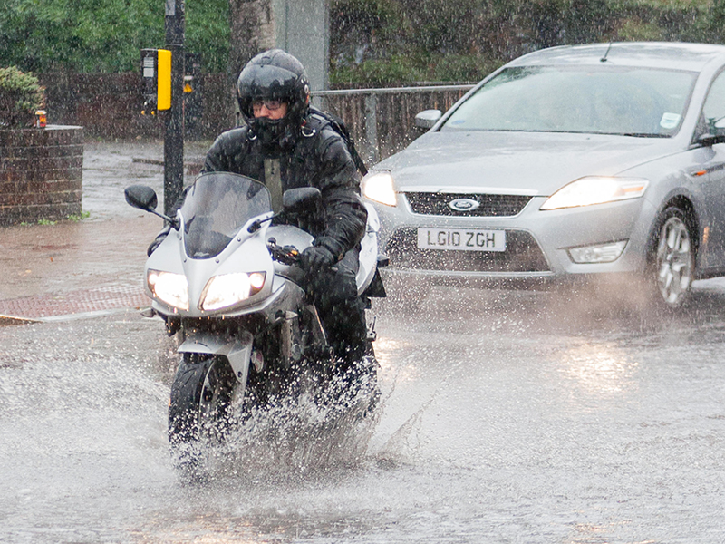 Guy riding through rain on motorcycle